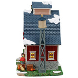This image shows what the side of this building looks like. There's a water tower standing next to the house. There's some snow on the roof and on the grass.