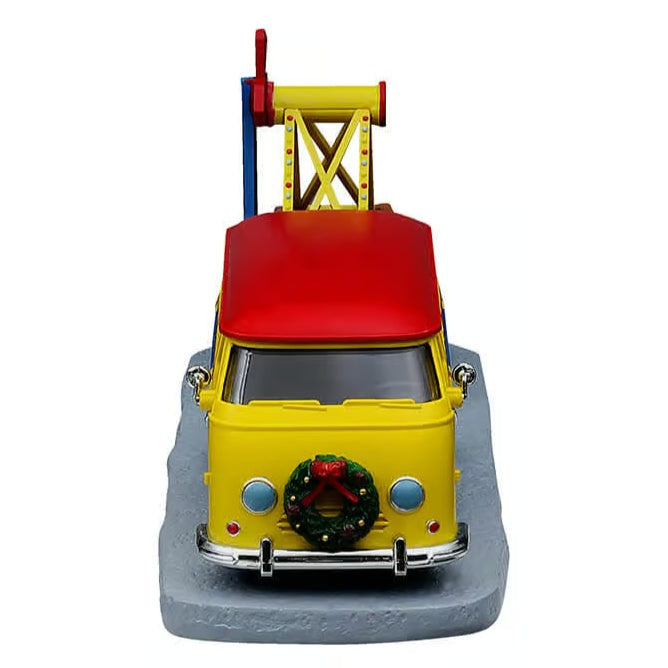 This image shows what the vintage van looks like from head-on. The van is yellow with a red roof. There's a decorated wreath hanging on the front bumper.