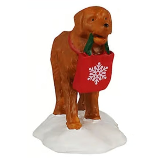 This image shows what the dog figurine looks like on a white background. The dog looks like a golden retriever. He's wearing a red collar and holding a shopping bag with his mouth. The bag is red with a white snowflake on it.
