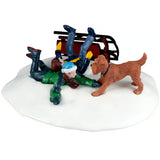 This image shows what this Lemax table accent looks like on a white background. It was designed to look like two boys have crashed their sled in the snow and a dog came up to see if they were okay. The sled is a maroon color.