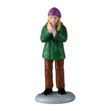 This figurine was designed to look like a woman clapping. She has blonde hair and is wearing a purple hat, a green jacket, brown pants and black shoes.