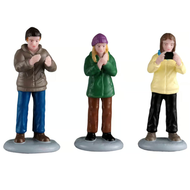 This image shows what these three Lemax General Collectible figurines look like on a white background. They were designed to look like people watching a performance, clapping and taking pictures.