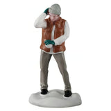 This figurine was designed to look like a boy shielding his face from snowballs. He's wearing a gray knit hat, a white long sleeve shirt, a brown vest, green gloves, grey pants and black shoes.