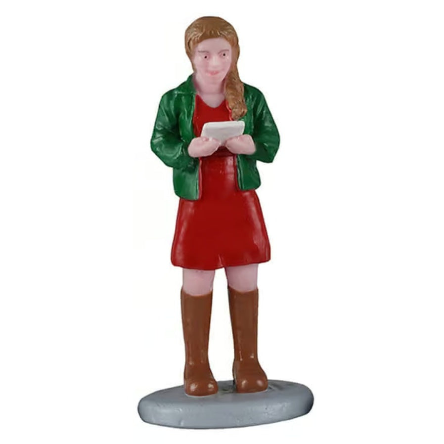This image shows a woman figurine holding a sheet of music and singing. She has light brown hair and is wearing a green jacket, a red dress and brown knee-high boots.