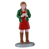 This image shows a woman figurine holding a sheet of music and singing. She has light brown hair and is wearing a green jacket, a red dress and brown knee-high boots.