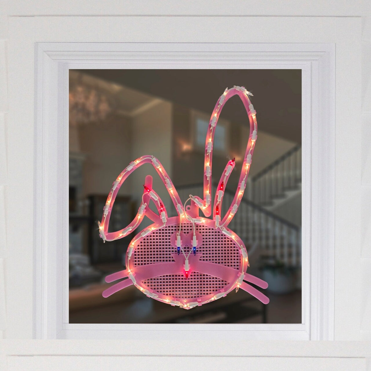 This is a lifestyle image showing what this lighted bunny head decoration looks like on a window.