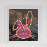 This is a lifestyle image showing what this lighted bunny head decoration looks like on a window.