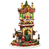 This image shows what this Lemax building looks like on a white background. It was designed to look like a tall Christmas-themed tower. There are nutcrackers and a tree on the roof. There's a countdown to Christmas and there are lots of wrapped presents everywhere. Santa is at the base of the tower, where a toy train goes in circles.