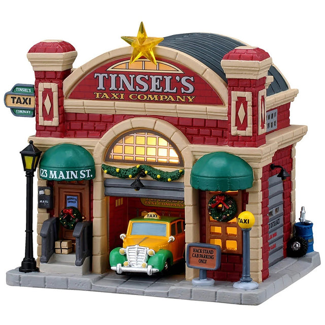 This image shows what this Lemax building looks like on a white background. It was designed to look like a red barn turned into a garage for taxis. There's a large, gold star on the roof. There are decorative garlands and wreaths. Inside the garage, there's a yellow and green colored taxi.