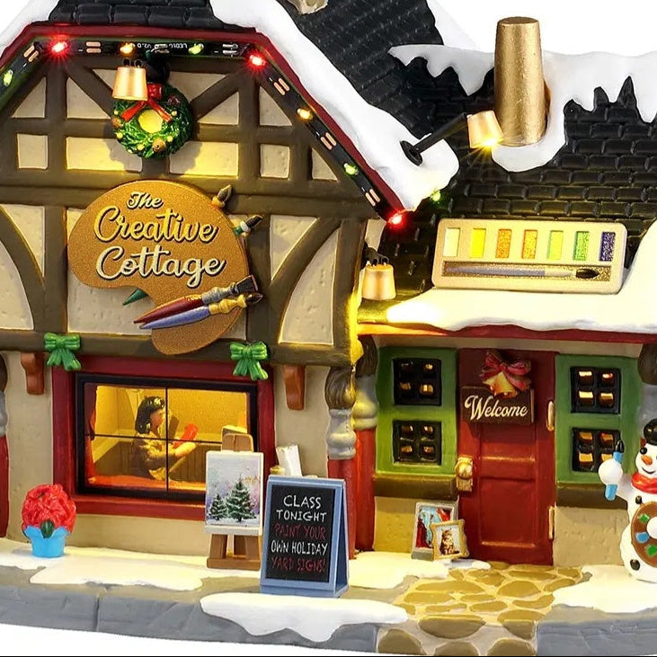 This is an up close view of this lighted building. There's a sign near the front door that reads "Class Tonight! Paint Your Own Holiday Yard Signs!"