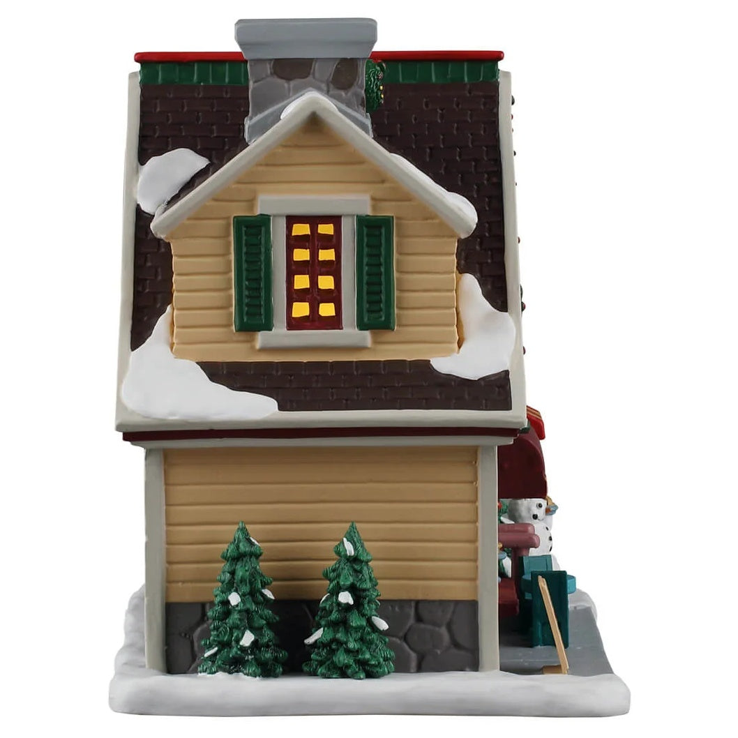 This image shows what the other side of this building looks like. There's a window with green shutters and two trees covered in snow.
