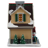 This image shows what the other side of this building looks like. There's a window with green shutters and two trees covered in snow.