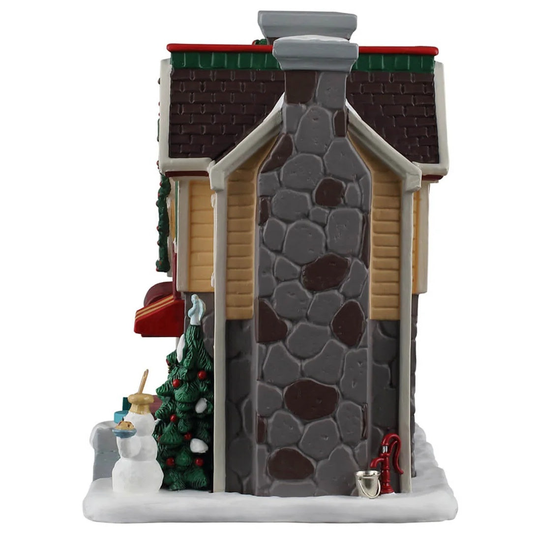 This image shows what the side of this building looks like. There's a tall, stone chimney and a red water well.