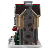 This image shows what the side of this building looks like. There's a tall, stone chimney and a red water well.