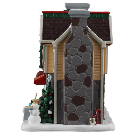 This image shows what the side of this building looks like. There's a tall, stone chimney and a red water well.