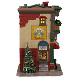 This image shows what the side of this building looks like. There's a yellow sign that reads "Buon Natale" which translates to "Merry Christmas" in Italian and the sign features two angels. There's a pizza pick up window with a person standing behind the counter. 