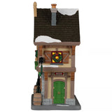 This image shows what this building looks like from the side. There's some snow on the roof and on the sidewalk. There's a wreath in the window and a sign that reads "BEER" above the green side door.