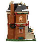 This image shows what the side of this building looks like. There's a large decorated wreath hanging on the chimney and a large red sign that reads "Garden Club Christmas Party."