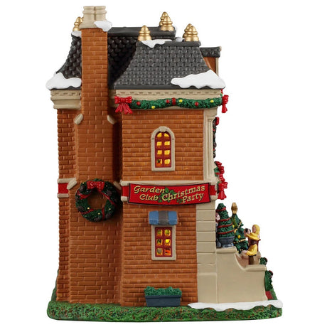 This image shows what the side of this building looks like. There's a large decorated wreath hanging on the chimney and a large red sign that reads "Garden Club Christmas Party."