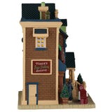 This image shows what the other side of this house looks like. There's a sign that reads "Fergie's Figgy Pudding Shoppe." There's a side door, as well as tables near the front of the building.