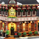 This is an up close view of this lighted building. There are signs that read "Est. 1922," "Dani's Pub," "Bar & Lounge" and "Ales, Stouts, Wines, Spirits." There's also a sign on the sidewalk near the front door that reads "Christmas Sweater Party Tonight!"