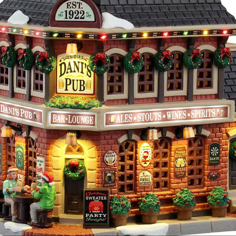 This is an up close view of this lighted building. There are signs that read "Est. 1922," "Dani's Pub," "Bar & Lounge" and "Ales, Stouts, Wines, Spirits." There's also a sign on the sidewalk near the front door that reads "Christmas Sweater Party Tonight!"