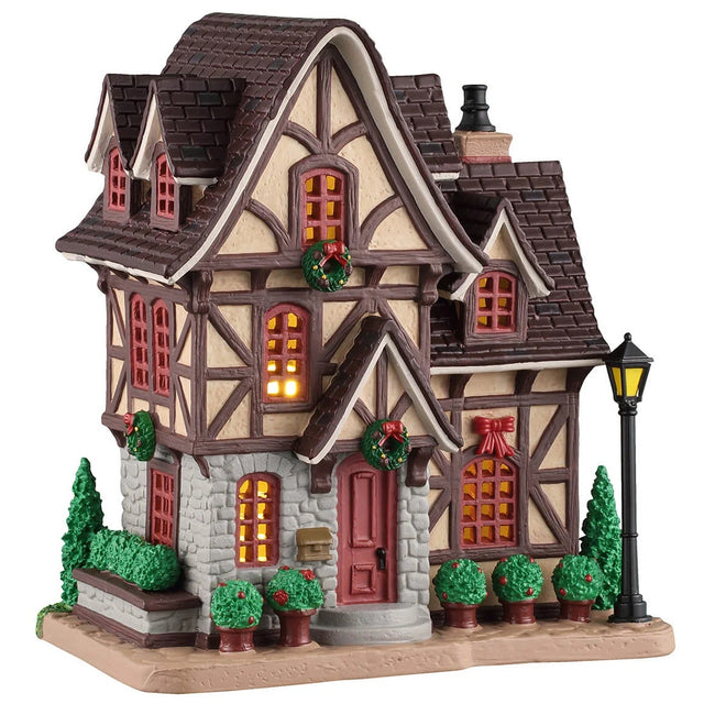 This image shows what this Lemax building looks like on a white background. It was designed to look like a tall cottage that has lots of potted plants, bushes and trees.
