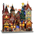This image shows what this Lemax Caddington Village building facade looks like on a white background. It was designed to look like a strip mall made up of old-timey, Victorian-era-type buildings. They're all decorated for Christmas with garlands. There's a giant decorated Christmas tree with Santa and his reindeer flying high above the building.