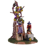 This is another angle of this piece. You can see a witch on a ladder draping the lights around the tree branches while another witch digs in a box of ornaments.