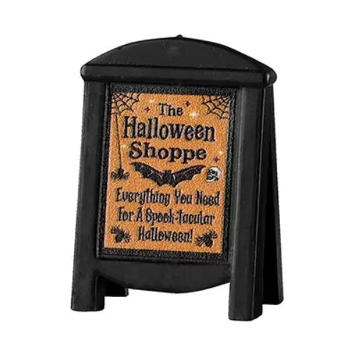This Lemax sign is a light orange color, as well as black. It reads "The Halloween Shoppe. Everything you need for a spook-tacular Halloween."
