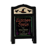 This Lemax sign is colored black with pale yellow, burnt orange, lime green and purple color accents. It reads "Witches Spells for Halloween and every day."