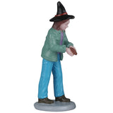 This image shows one of the figurines that was designed to look like a mom wearing a pale teal jacket, a purple shirt, blue jeans and a black witch's hat. She has candy in here hand and she's ready to give it away.