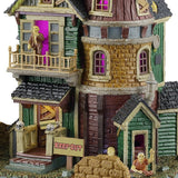 This is an up close view of the house. The house is painted a bunch of different unique colors like forest green, bronze yellow, black and brown and has a purple glow coming from inside.