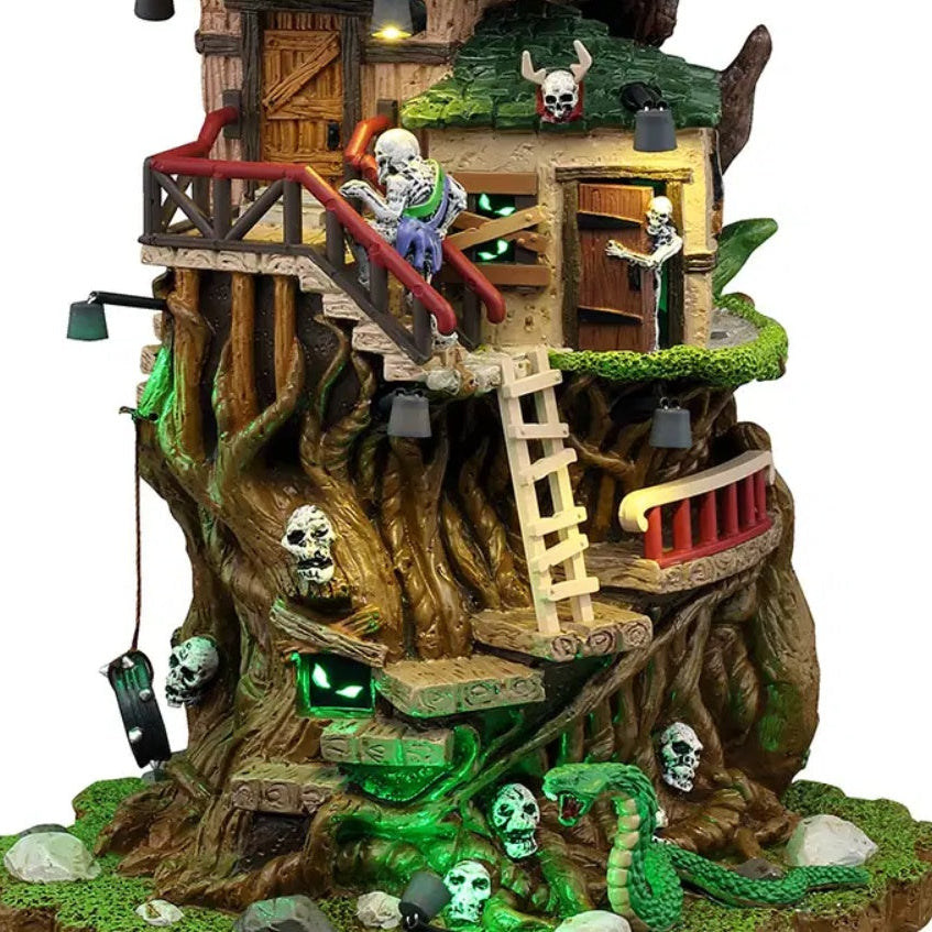This is an up close view of the lighted building. There's a skeleton walking up the stairs and a skeleton peering from behind a door. There's a tire swing and a little nook with two green, glowing eyes looking out.