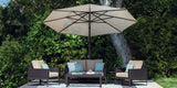 This is a lifestyle image showing this champagne colored umbrella on a stone patio with a wicker patio furniture set underneath.