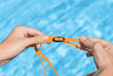 This is a lifestyle image showing someone adjusting the size of the orange goggles.