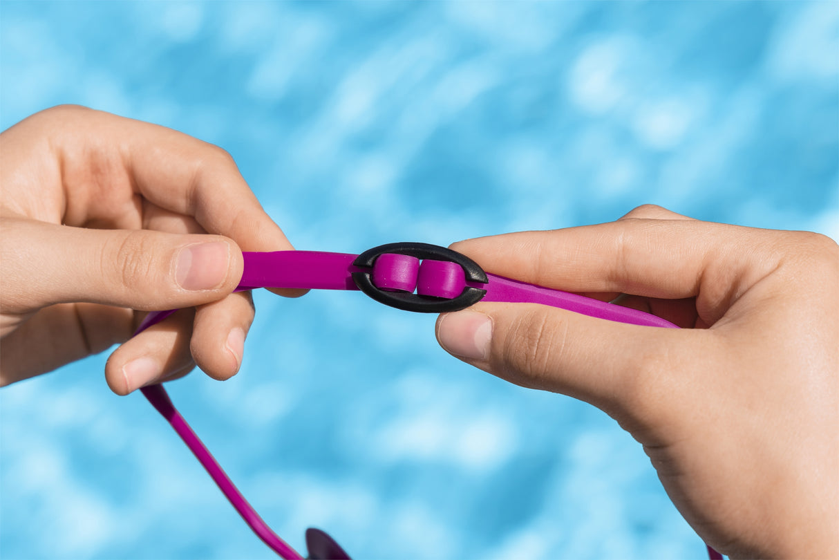 This is a lifestyle image showing someone adjusting the size of the magenta goggles.