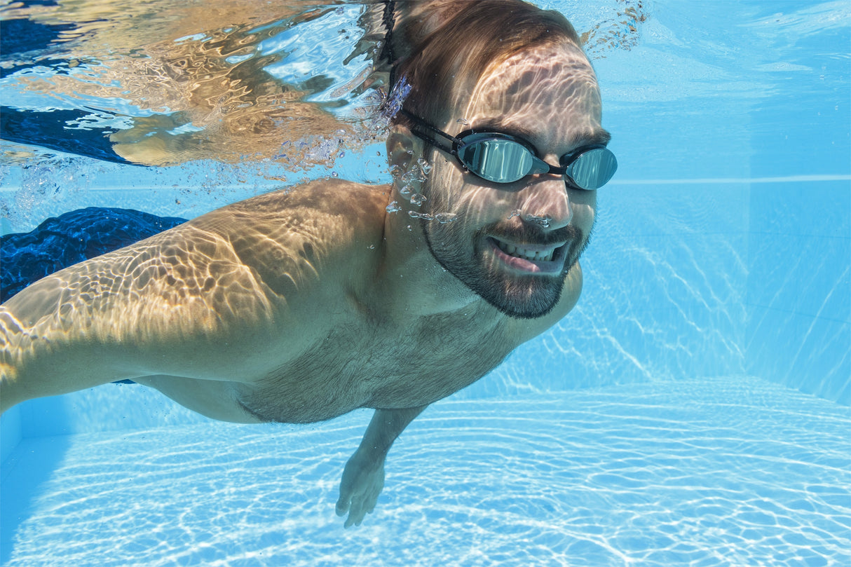 This is a lifestyle image showing a man swimming underwater wearing the black goggles.