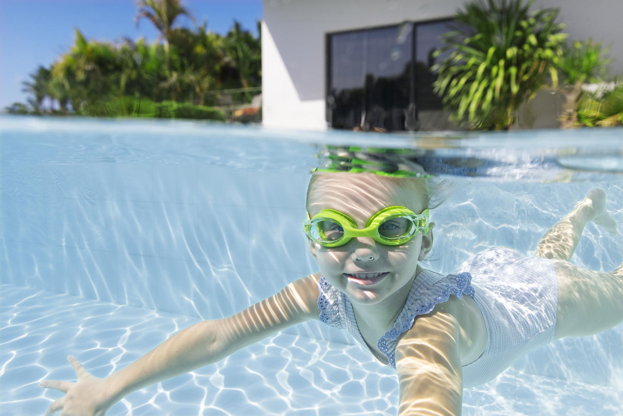 This is a lifestyle image showing a young girl swimming underwater wearing the lime green colored goggles.