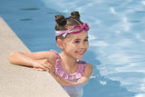 This is a lifestyle image showing a young girl with the magenta goggles on her forehead near a pool.