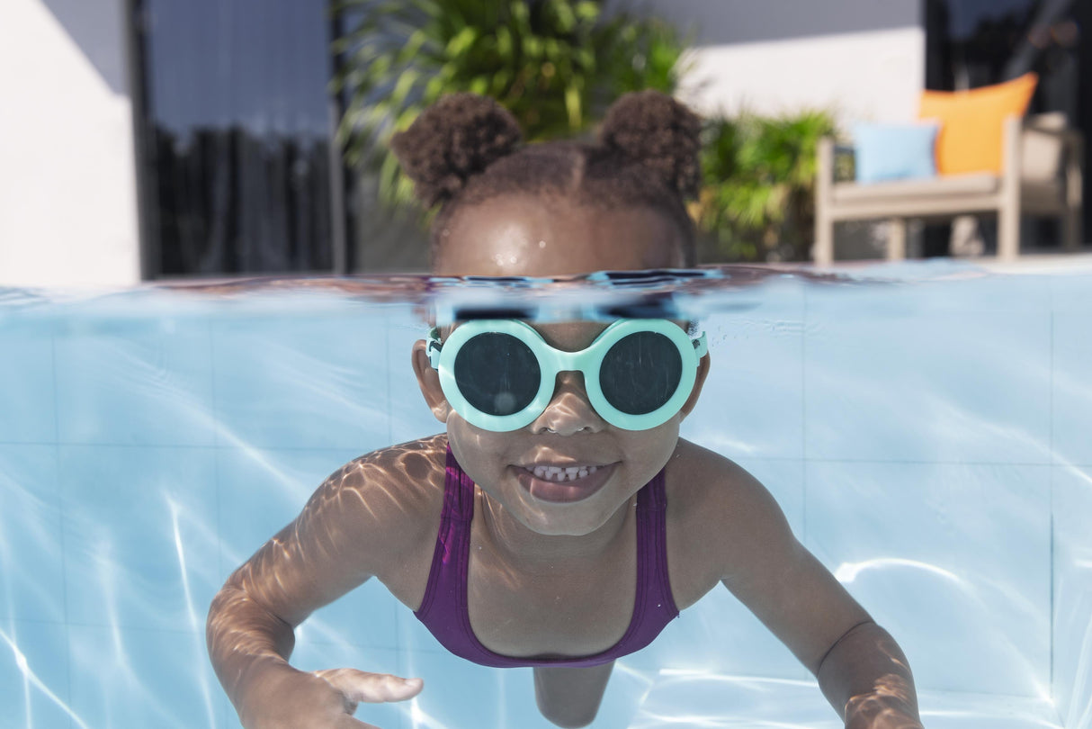 This is a lifestyle image showing a young girl swimming underwater wearing the neon blue colored goggles.