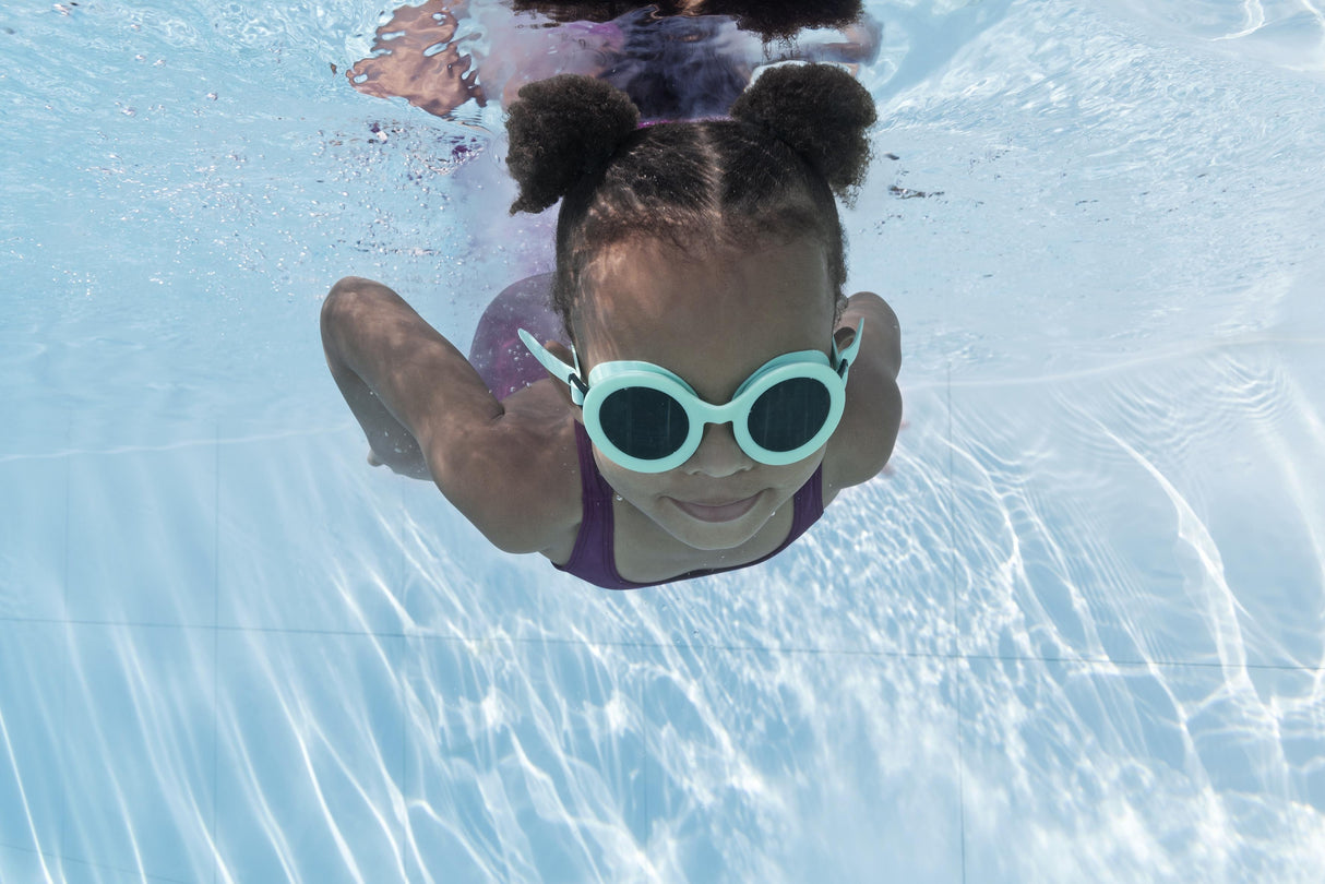 This is a lifestyle image showing a young girl swimming underwater wearing the neon blue goggles.