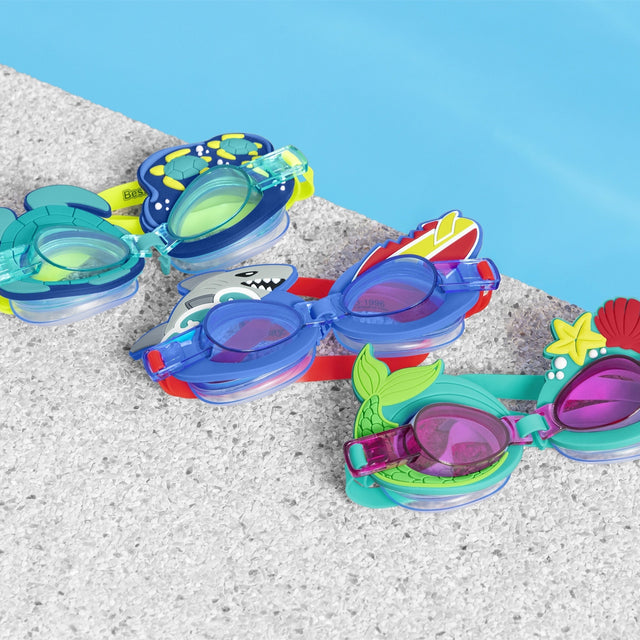 This is a lifestyle image showing all three goggle options displayed on the ground next to a pool.