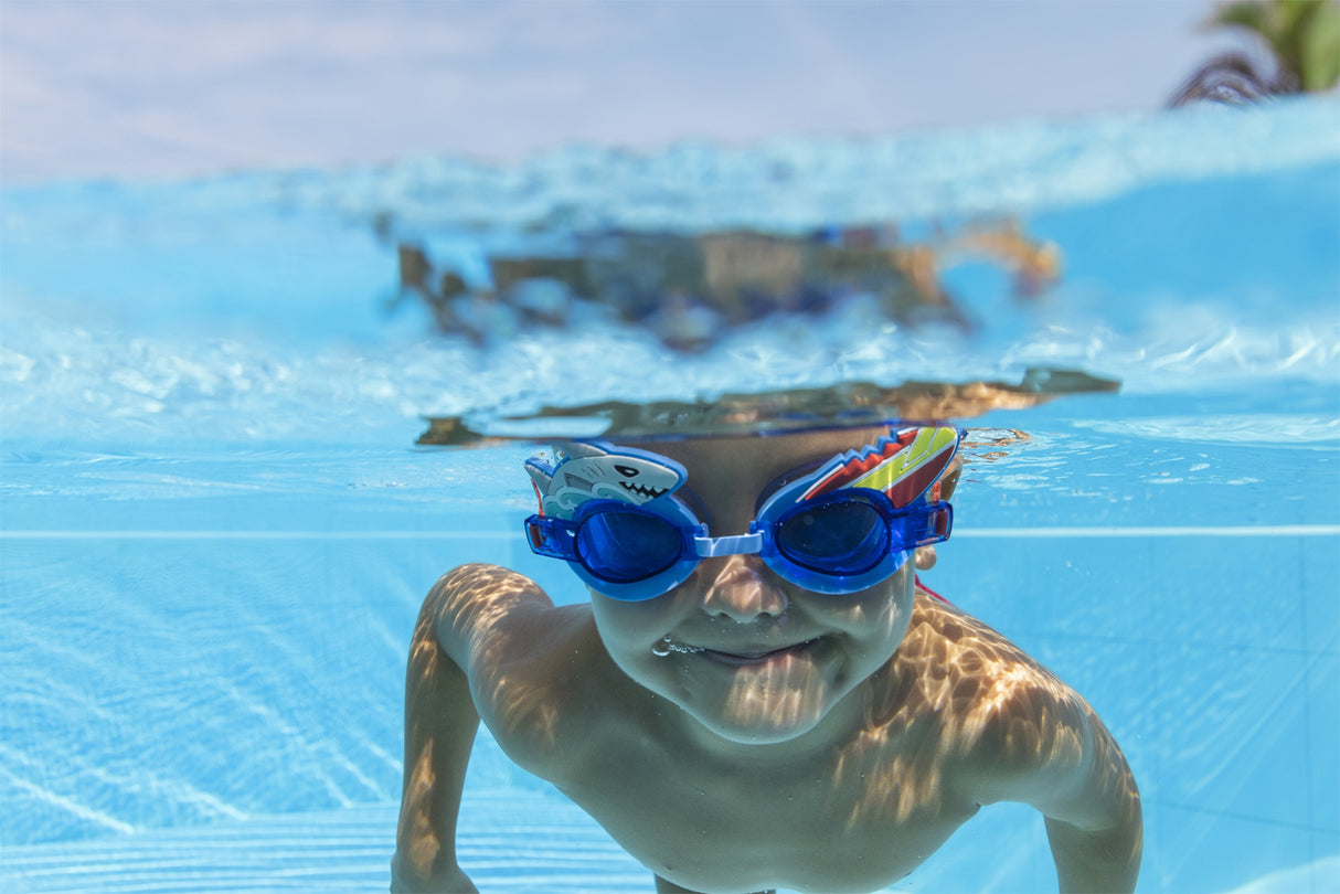 This is a lifestyle image shows a young boy swimming underwater wearing the shark themed goggles.