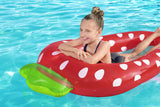 This is a lifestyle image showing a young girl laying on her stomach inside the strawberry float in a pool.