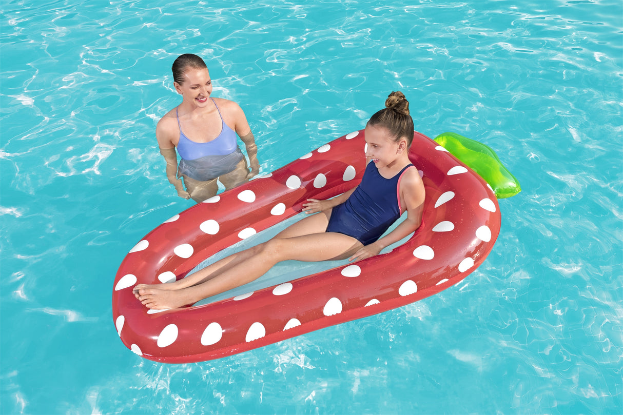This is a lifestyle image showing a young girl resting inside the strawberry float while her mom floats nearby.