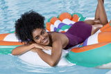 This is a lifestyle image showing a woman laying on the pool float and smiling at the camera.