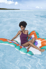 This is a lifestyle image showing a woman sitting on the pool float in the middle of the ocean.