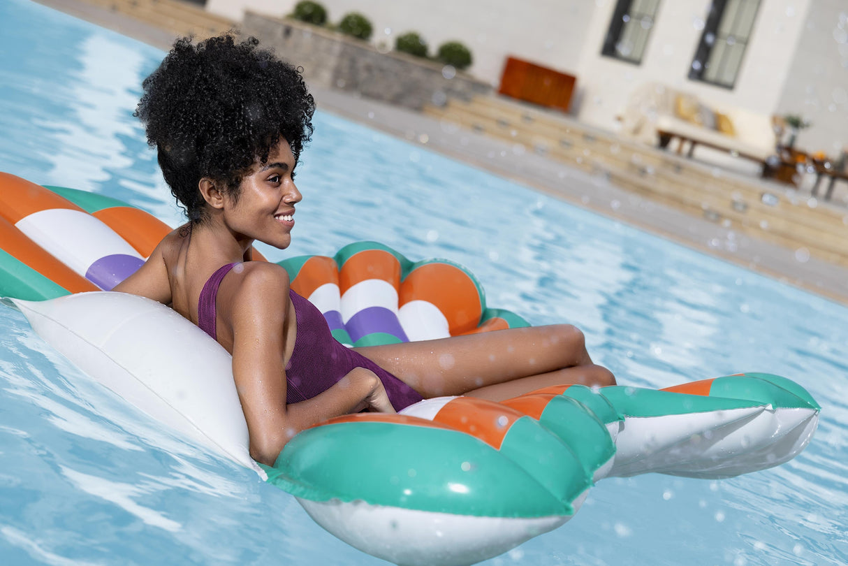 This is a lifestyle image showing a woman resting on the butterfly shaped pool float in a pool.