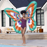 This is a lifestyle image showing a woman using this butterfly shaped pool float as wings behind her.